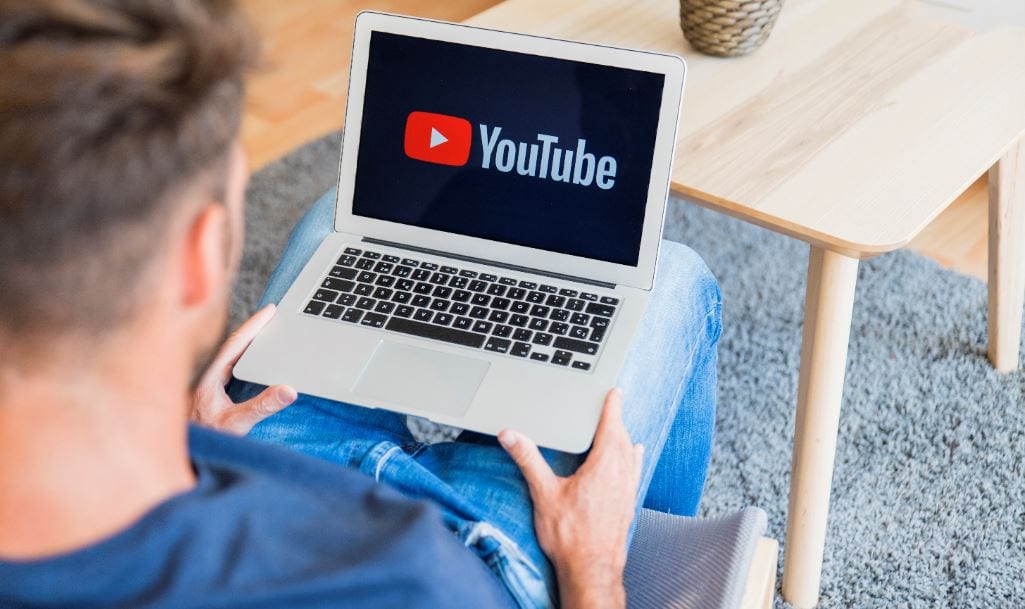 como divulgar um canal do Youtube: Imagem de um homem segurando o notebook no colo.