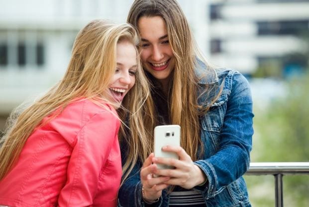 Como usar gifs: imagem de duas pessoas sorrindo olhando para o celular.