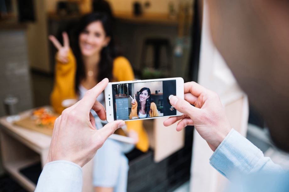 Foto de perfil do Instagram: imagem de uma mulher fazendo pose para foto e outra pessoa fotografando pelo celular.