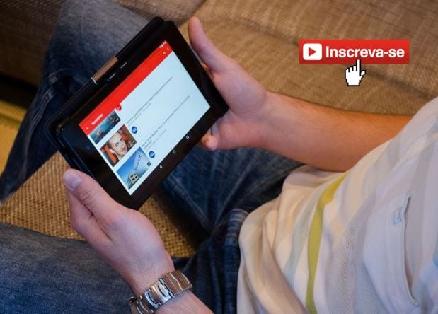 Como ganhar inscritos no YouTube: imagem de uma pessoa, sentada no sofá, segurando um tablet assistindo vídeo no YouTube.