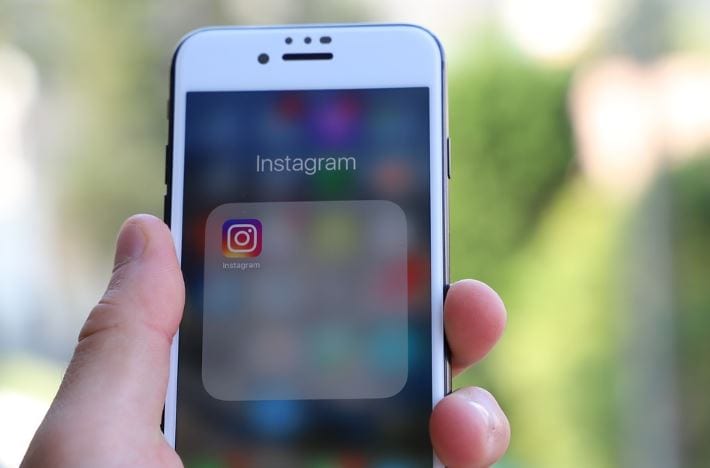 Como aumentar o alcance no Instagram: imagem de uma mão segurando o celular com a tela mostrando o ícone do Instagram