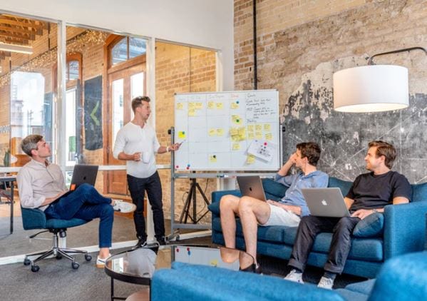 Branding Pessoal: imagem de quatro pessoas fazendo uma reunião com um quadro e post-its colados