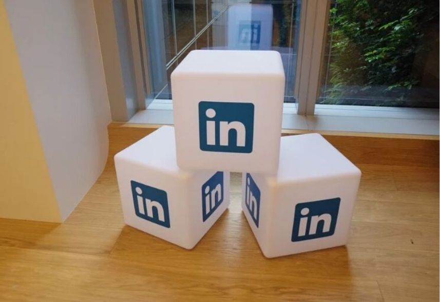 Linkedin Premium: imagem de três dados com a logo do linkedin impressa em cada, alinhados dois dados embaixo e um dado em cima, numa sala com piso de madeira
