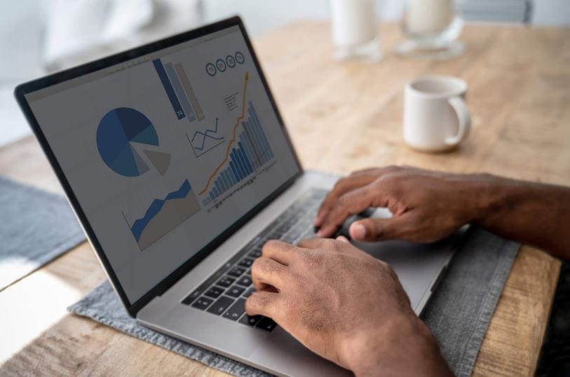 criar conta no google analytics: imagem de duas mãos masculinas digitando em um notebook sobre a mesa com gráficos aparecendo na tela