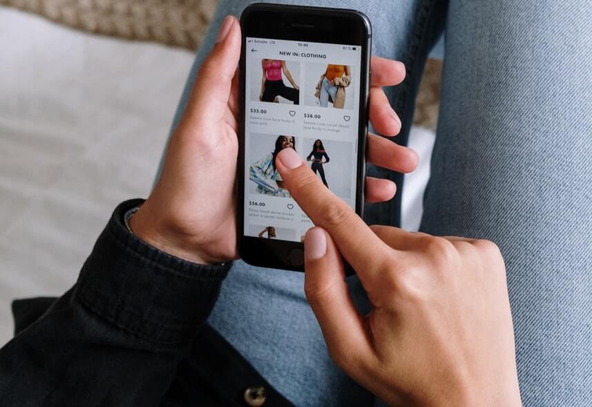 Google Shopping: imagem de uma pessoa usando o celular. Na tela, aparece uma página de compra de roupas.
